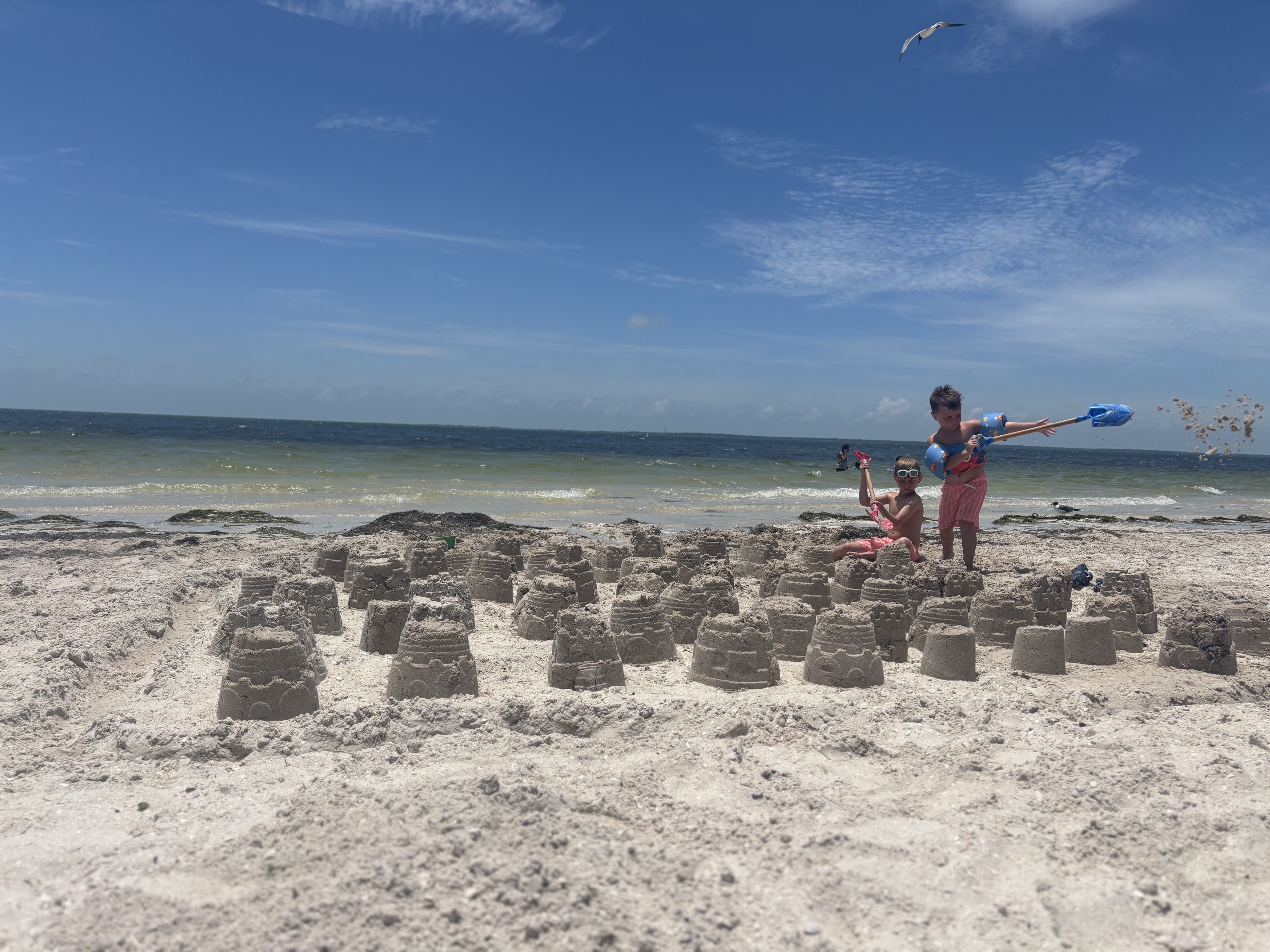 Two boys building an entire village of sandcastles along the shoreline