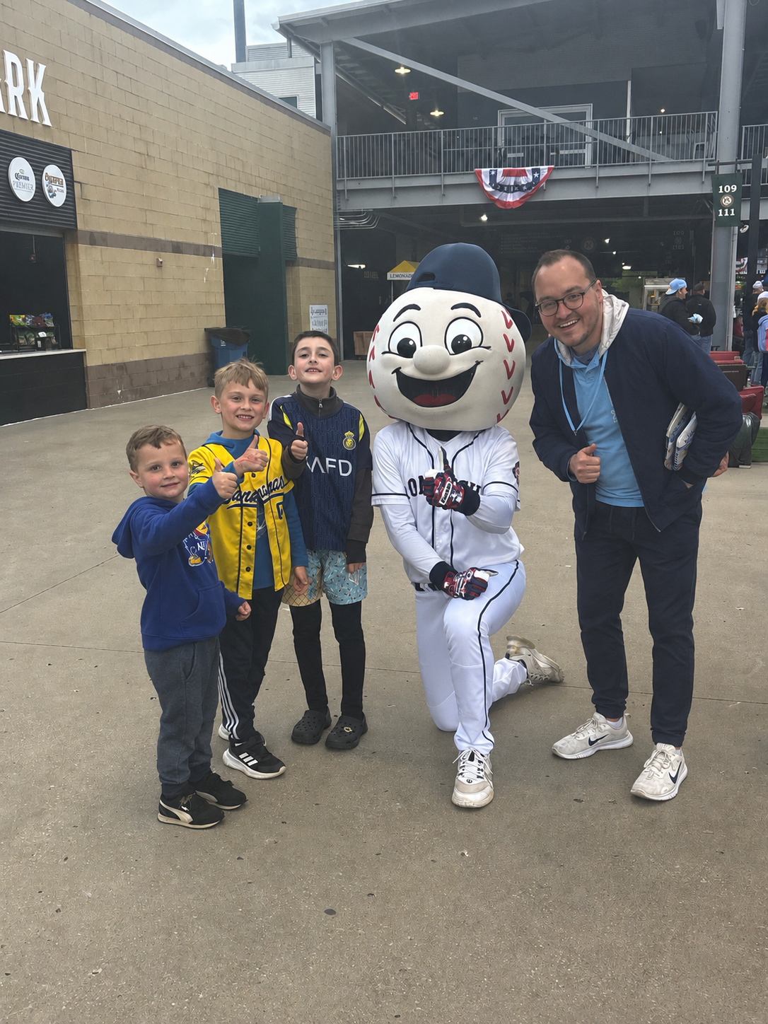 Chris and the boys with a baseball mascot at the ballpark